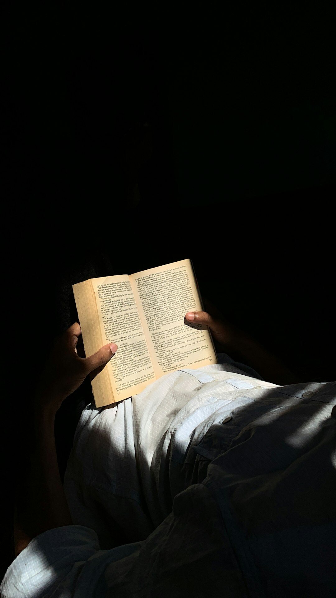 person reading book in dim light